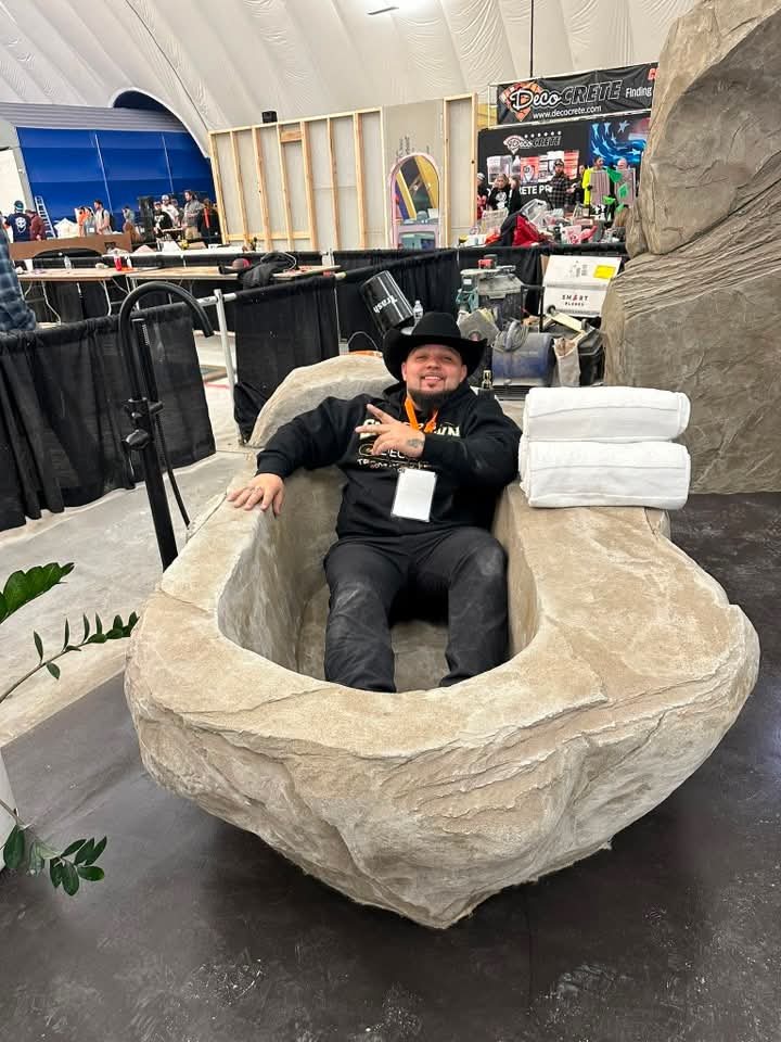 Christopher Land of Epoxy Guys seated in a carved concrete piece, confirmed guest at The Golden Pour Awards 2026