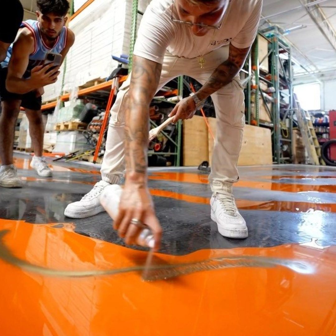 Don Resin dusting pigment across an orange metallic epoxy pour, confirmed guest at The Golden Pour Awards 2026